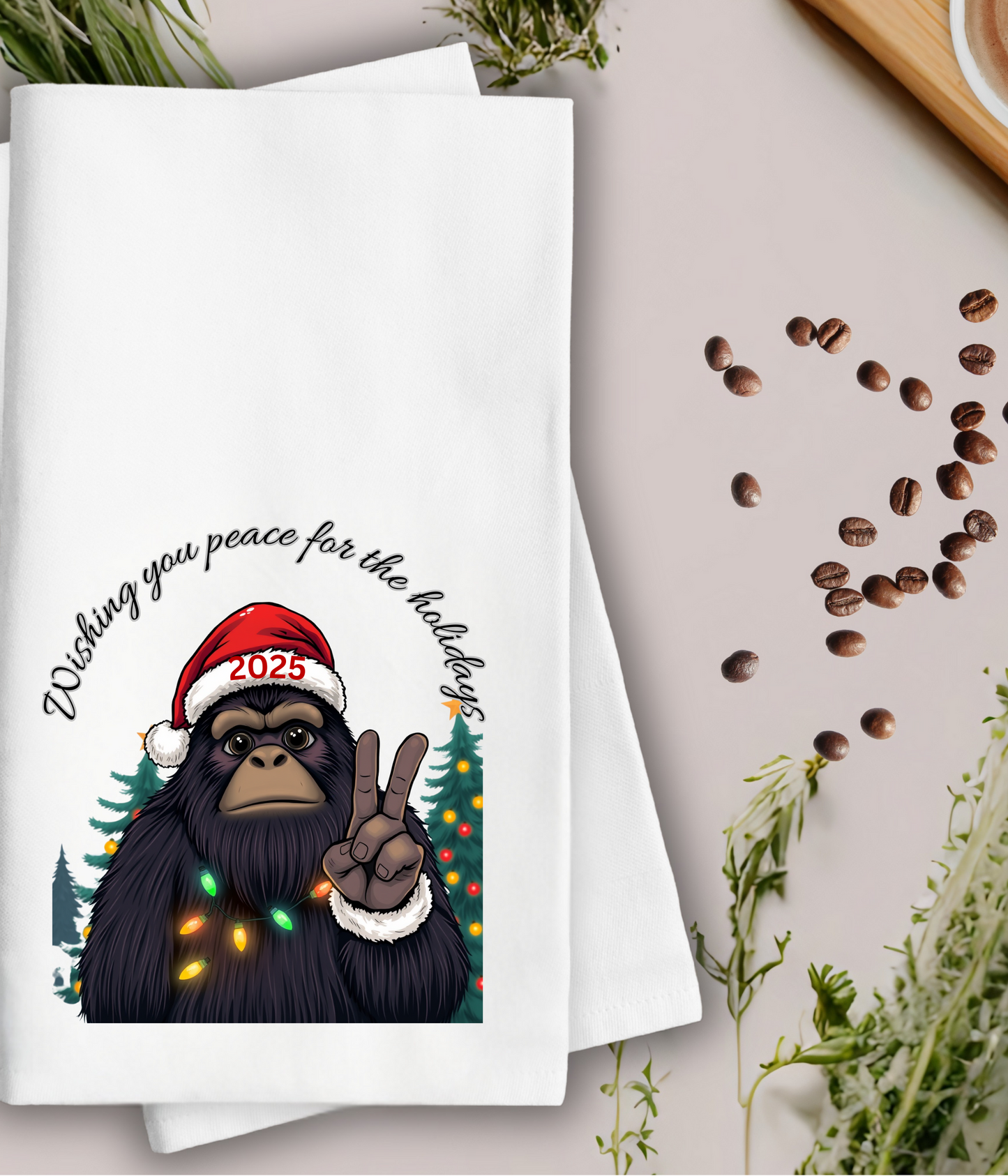 Towel with a cartoon yeti wearing a Santa hat and peace sign, surrounded by coffee beans and a cup of coffee.